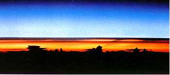 Onweerswolken bij zonsopgang, gezien vanuit de Spaceshuttle Atantis. De vlakke, aambeeldvormige wolkentoppen markeren de bovengrens van de troposfeer.